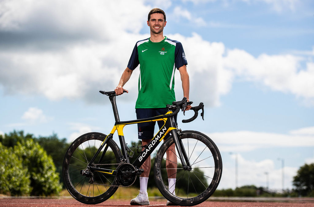 James Edgar standing with his bike. James is wearing his Commonwealth Games training kit.
