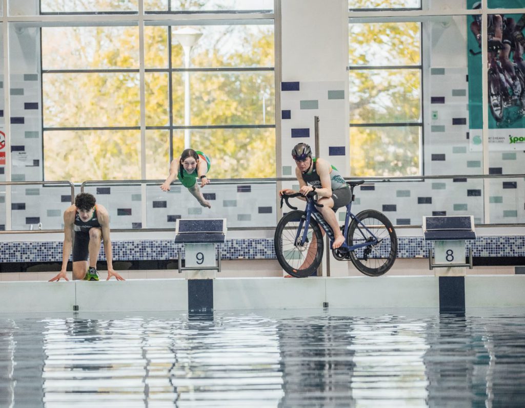 National Triathlon centre photo athletes by pool posing to swim, cycle and run