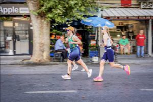 Tri Team Ireland triathlete running through streets past shop fronts