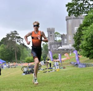 Youth Triathlon Commission Members 2026 - Boy running in orange tri suit by castle