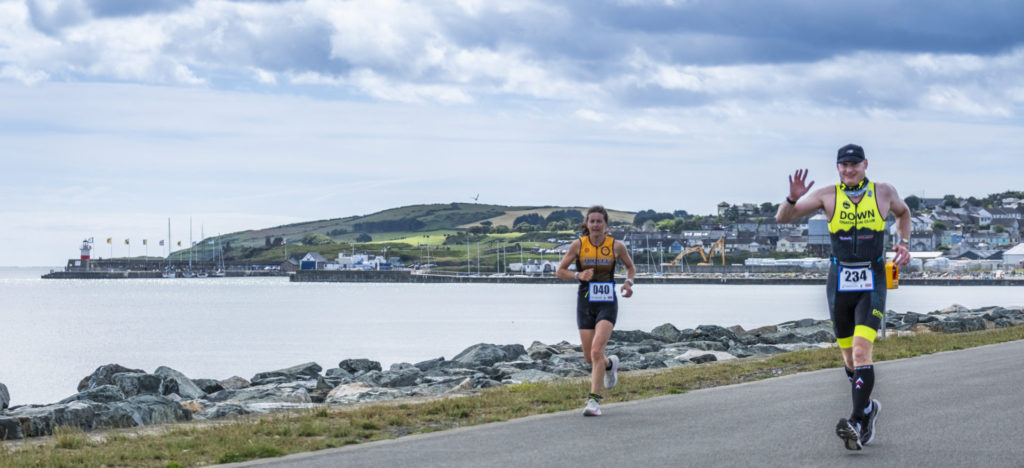 Photo of triathletes running harbour wall